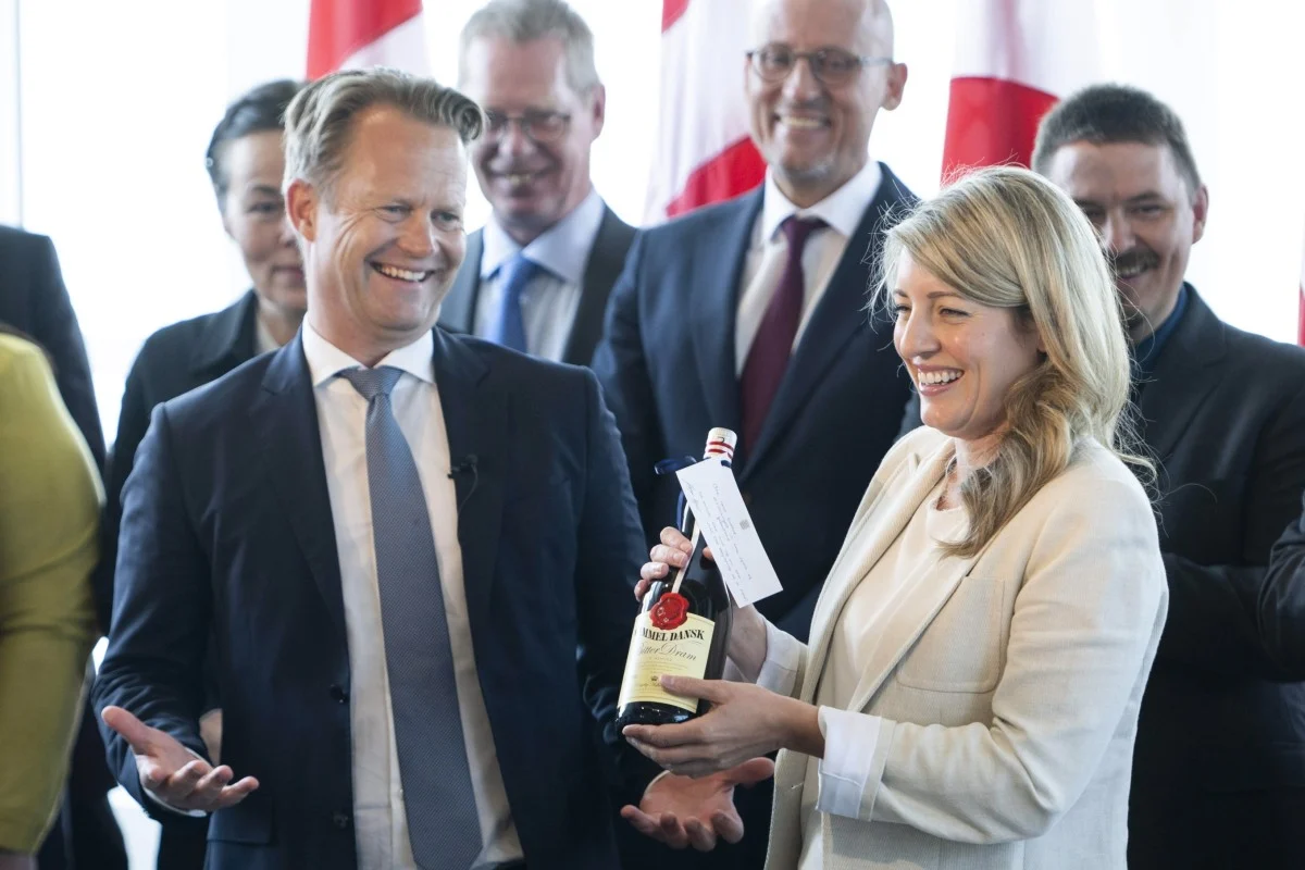 Photo of Canadian Foreign Minister Mélanie Joly and Danish Foreign Minister Jeppe Kofod exchanging bottles of spirits at the official treaty ceremony