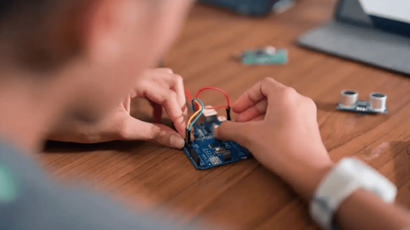 Student working on an electronics project with Arduino components for STEM education and technology learning.