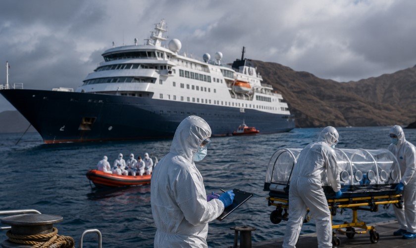 Medical emergency teams in hazmat suits evacuate passengers near a cruise ship during the MV Hondius hantavirus outbreak in the Atlantic Ocean.