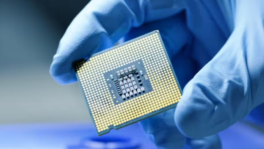 Close-up of a semiconductor chip being held with gloves, representing India Semiconductor Mission 2.0 and domestic chip manufacturing.